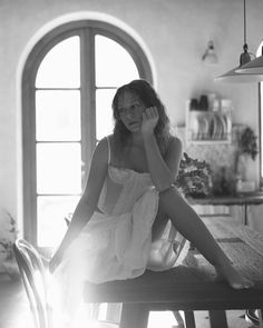 a woman sitting on top of a wooden table