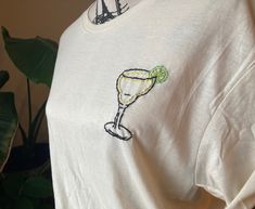 a white t - shirt with a lime and a glass on it