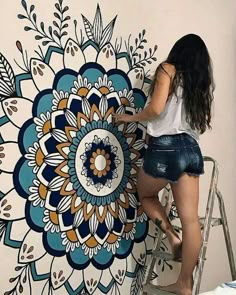 a woman is painting a large flower on the wall