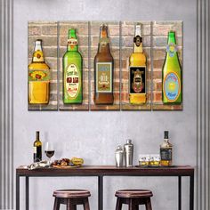 a table topped with bottles of alcohol next to two stools in front of a wall