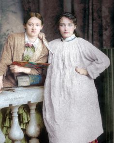 two women standing next to each other in front of a table with books on it