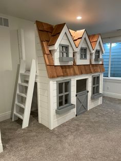 a house made out of cardboard with windows and doors on the roof is shown in an empty room