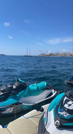 two jet skis parked next to each other in the water near another boat and motorboat