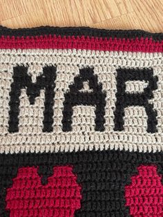 a close up of a crocheted bag on a wooden surface with the word minecraft written in black, white and red