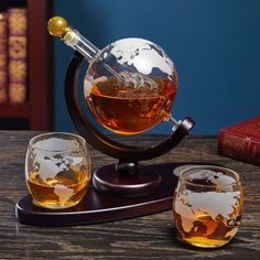 two glasses filled with liquid sitting on top of a wooden table next to a globe