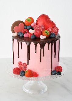 a pink cake with chocolate icing and fruit on top