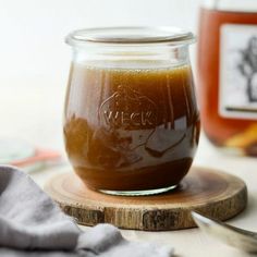 a glass jar filled with liquid sitting on top of a wooden board next to garlic