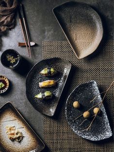 three plates with food on them and chopsticks next to one plate that has sushi in it