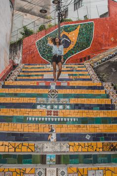 a woman standing on the top of some steps with an umbrella in her hand and colorful tiles all around her