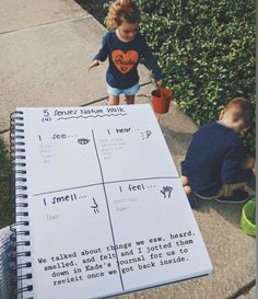 two children are playing outside on the sidewalk and one is holding a notebook with writing