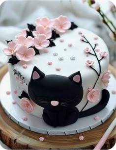 a white cake decorated with black cat and pink flowers