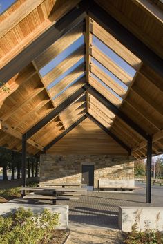 an outdoor covered area with benches and tables under a roof that is made of wood