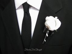 a man in a suit with a white rose pinned to his lapel flower on it's lapel