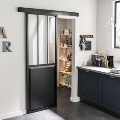 an open door leading into a kitchen with black cabinets