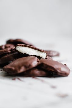 chocolate covered cookies with white frosting on a marble counter top, one broken in half