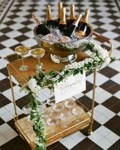 a bar cart filled with champagne bottles and glasses on top of a checkered floor