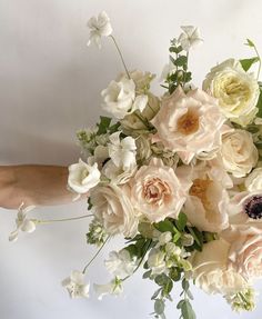 a bouquet of white and pink flowers in someone's hand on a white background