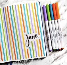 some markers are laying on top of an open notebook with the word june written in it