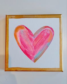 a painting of a pink heart in a gold frame on a white wall with a yellow border