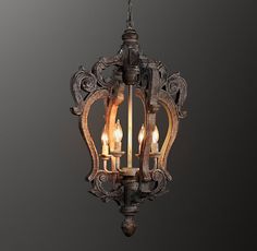 a chandelier with three lit candles hanging from it's center and an intricately carved frame