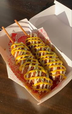 hotdogs with cheese and ketchup in a box on a wooden table