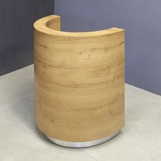 a curved wooden counter sitting on top of a white tile floor next to a gray wall