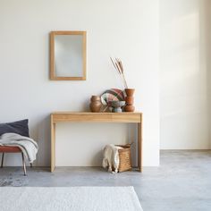 a room with a bench, mirror and vases on the table next to it