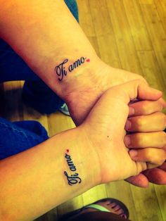 two people are holding hands with tattoos on their arms and the words ti amo in cursive writing