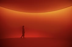 a person standing in the middle of a room with red light coming from behind them