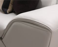 a white leather couch with two pillows on it's back end and the seat upholstered