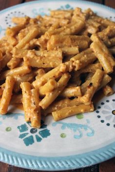 a plate full of pasta and sauce on a wooden table with blue flowered plates