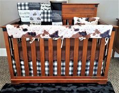 a wooden crib with black and white pillows on it