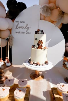 a table topped with lots of cupcakes covered in frosting and teddy bears