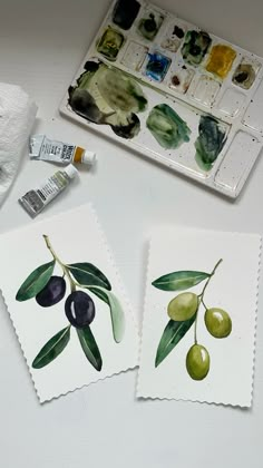 some olives are sitting on top of a table next to paintbrushes and paper towels