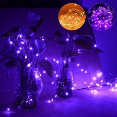 three vases filled with flowers and lights on top of a wooden table in front of a purple background