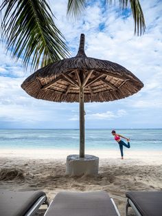 a woman doing yoga on the beach under an umbrella