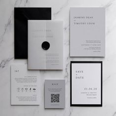 the wedding stationery is laid out neatly on top of the marble countertop, with black and white accents