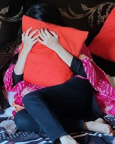 a woman is covering her face with pillows