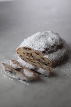 a loaf of bread is covered with powdered sugar and sits on a gray surface