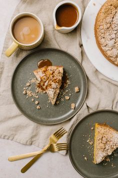 two plates with slices of pie on them next to cups of coffee and spoons