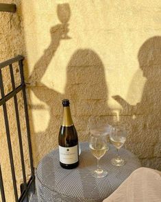 a bottle of wine sitting on top of a table next to two glasses of wine