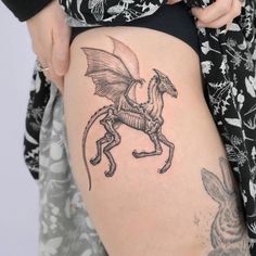 a woman's thigh with a dragon tattoo on it and an animal behind her