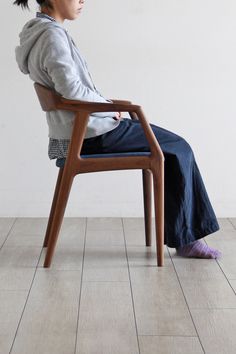 a woman sitting on top of a wooden chair