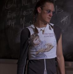 a man with glasses standing in front of a chalkboard