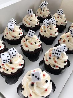 cupcakes decorated with white frosting and black polka dots are in a box