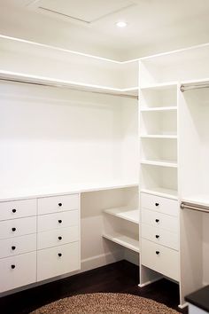 an empty closet with white shelves and drawers