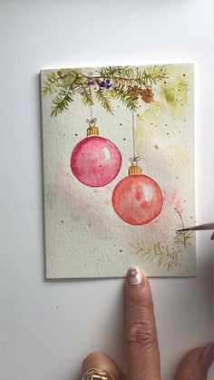 a person is painting christmas ornaments on a piece of paper