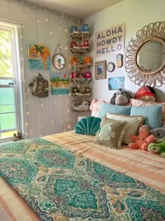 a bed with lots of pillows and stuffed animals on top of it next to a window