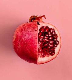 a pomegranate cut in half on a pink background