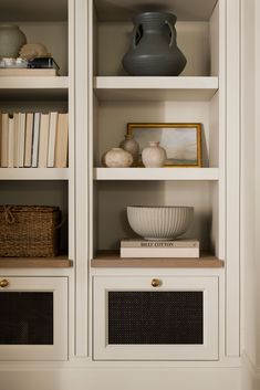 an open bookcase with books and vases on the top shelf in front of it